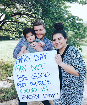 Justin and his family holds up a poster that reads "Every day may not be good, but there's good in every day." 