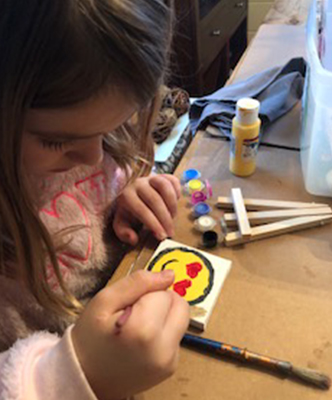 Kelly painting a heart eyes emoji. 